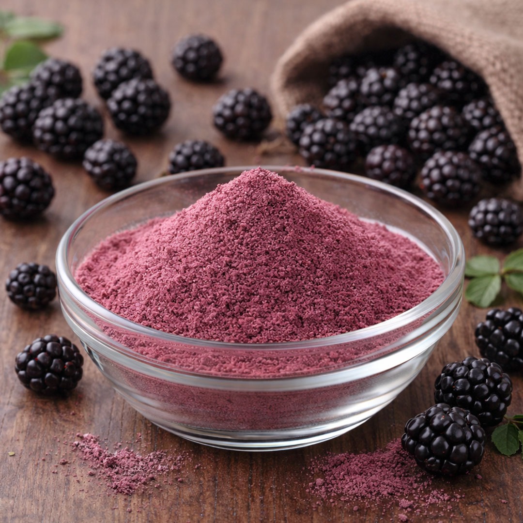 A bowl of vibrant purple blackberry powder surrounded by fresh blackberries on a rustic wooden surface.